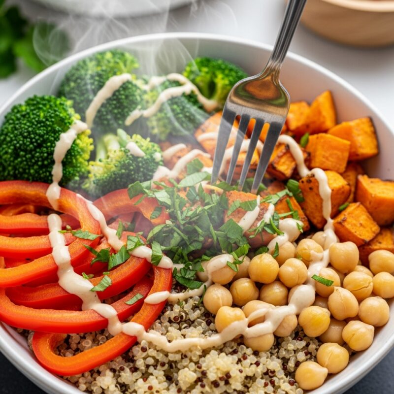  Colorful power bowl with quinoa, roasted sweet potato, steamed broccoli, chickpeas, red bell peppers, and tahini drizzle.